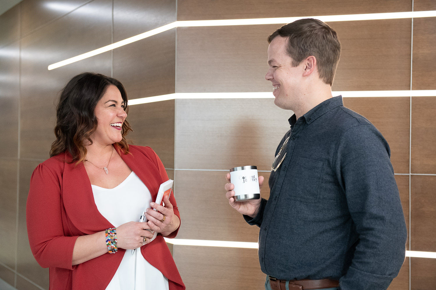 A native american woman speaks to a white man, they are both standing and smiling